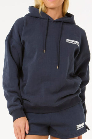 Wearing a navy blue Rip Curl Surf Puff Heritage Hood with matching shorts, featuring a small white "Rip Curl Surfing Company" logo, this person stands against a plain background.