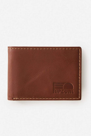 The Rip Curl Surf Revival RFID All Day Wallet is a brown leather wallet with visible stitching, RFID protection to prevent digital theft, and an embossed Rip Curl logo in the bottom right corner, shown on a plain white background.