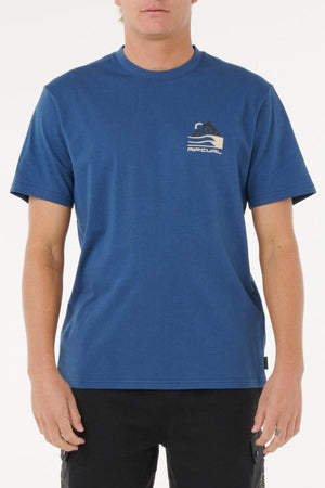 A person wearing a blue Rip Curl Vaporcool Search Range Tee with a small wave and sun logo on the left chest, paired with black pants, stands against a plain white background.