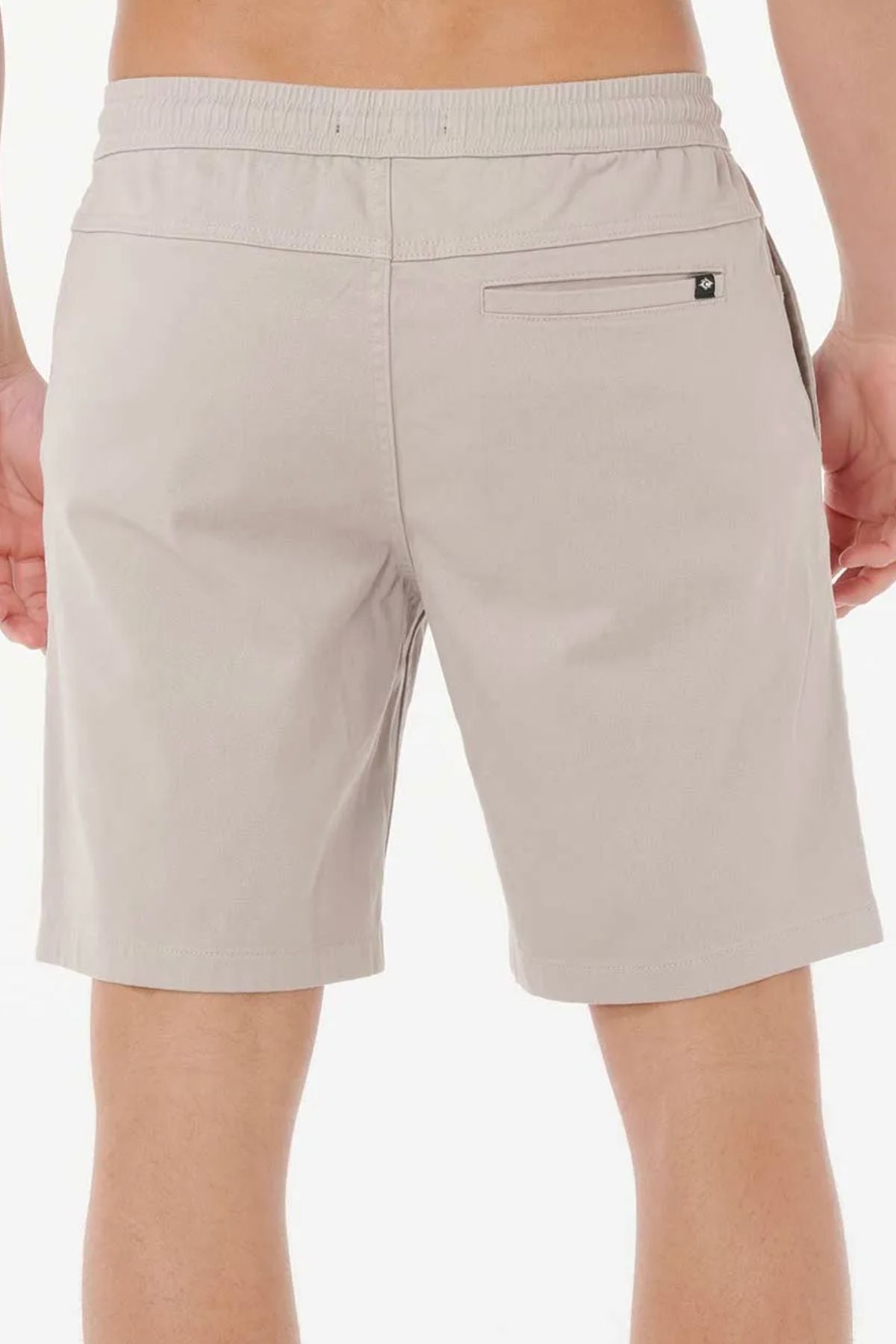 A person is shown from the waist down wearing Rip Curl Classic Surf Volley shorts in light beige, featuring an elastic waistband and a right back pocket, set against a plain white background.