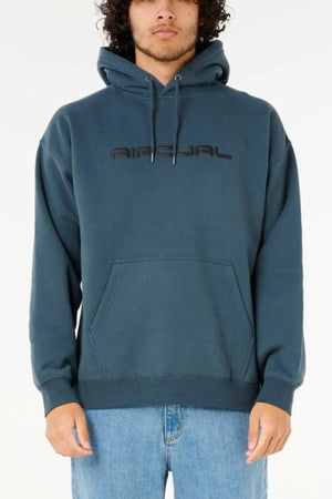 A person stands against a white background wearing the Rip Curl Dosed Up Hood in teal, featuring black chest text and crafted from cotton polyester fleece, paired with light blue jeans.
