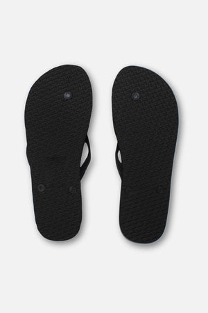 A pair of black Rip Curl Brand Logo Bloom Thongs, shown from the bottom against a white background, features textured soles, two circular plugs per sandal, and an ergonomic moulded design.