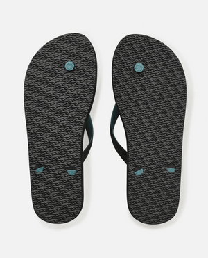 A pair of Rip Curl Breakers Bloom Thongs in black with BLOOM algae-blended foam, textured soles, and dark teal circular accents. They feature eco-friendly black straps, displayed on a plain white background.