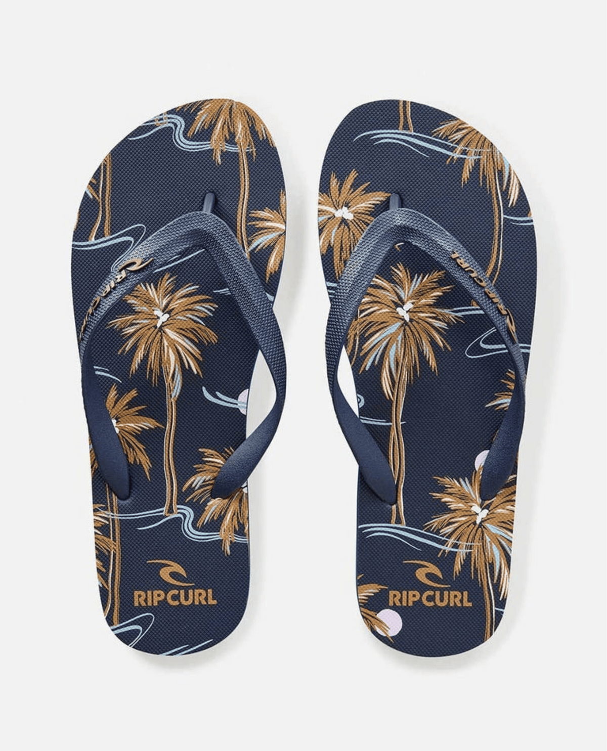 The Rip Curl Brush Palm Bloom Thongs feature a navy base with brown palm trees and abstract blue and white wave patterns. Crafted with an ergonomic strap and BLOOM™ algae foam, these thongs combine comfort and style for everyday adventures.