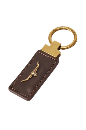 The RM Williams Angaston Key Ring is a brown smooth leather keychain with tan stitching, featuring a gold longhorn logo at the center and a brass key ring engraved with "R.M.WILLIAMS.