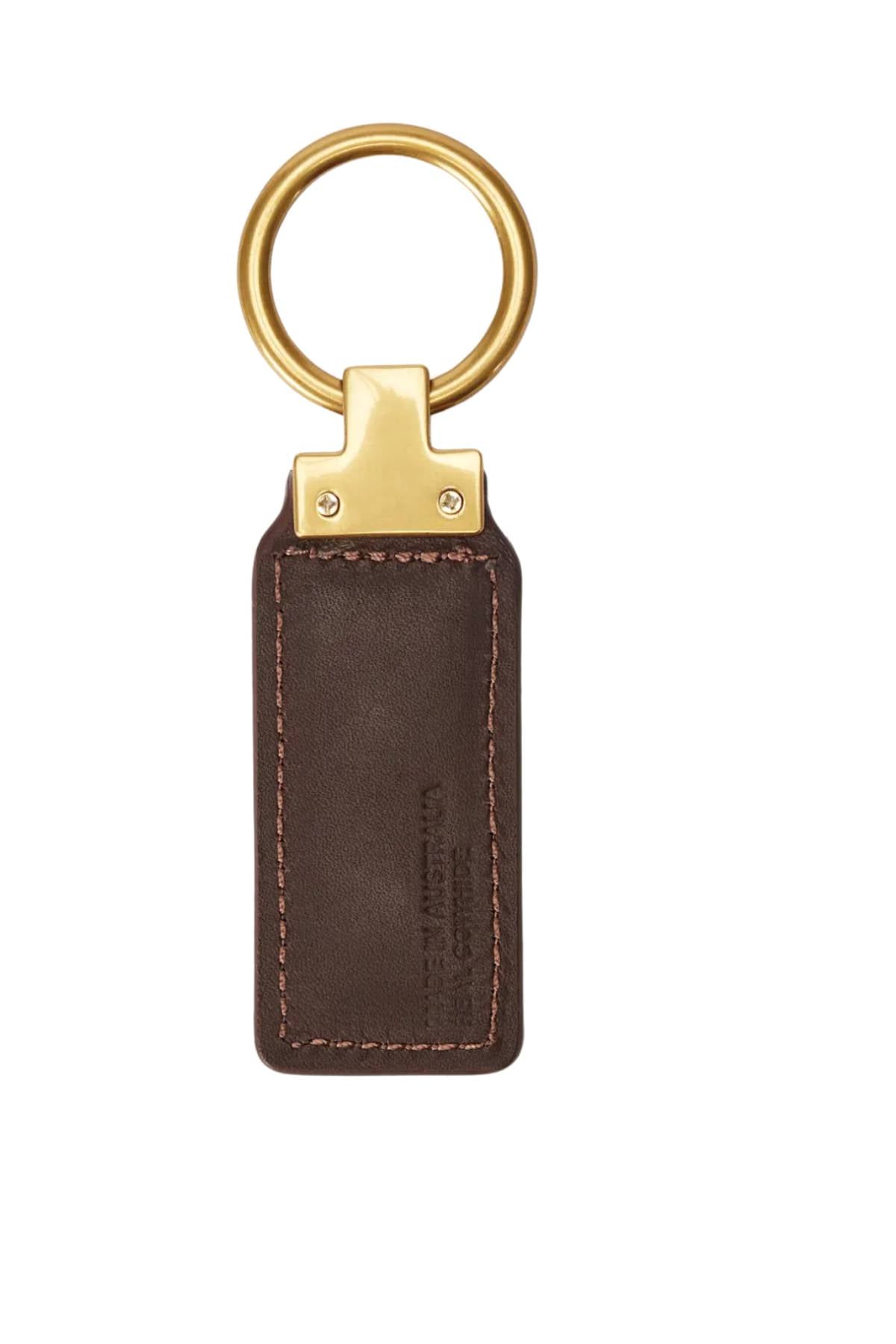 The RM Williams Angaston Key Ring is a brown smooth leather keychain with visible stitching, featuring the longhorn logo and a gold-colored metal keyring and clip, shown on a white background.