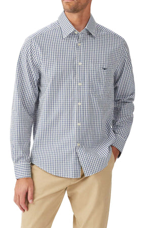 A man wearing the RM Williams Augusta Classic Poplin Shirt in blue and white checks and beige pants, standing with one hand in his pocket.