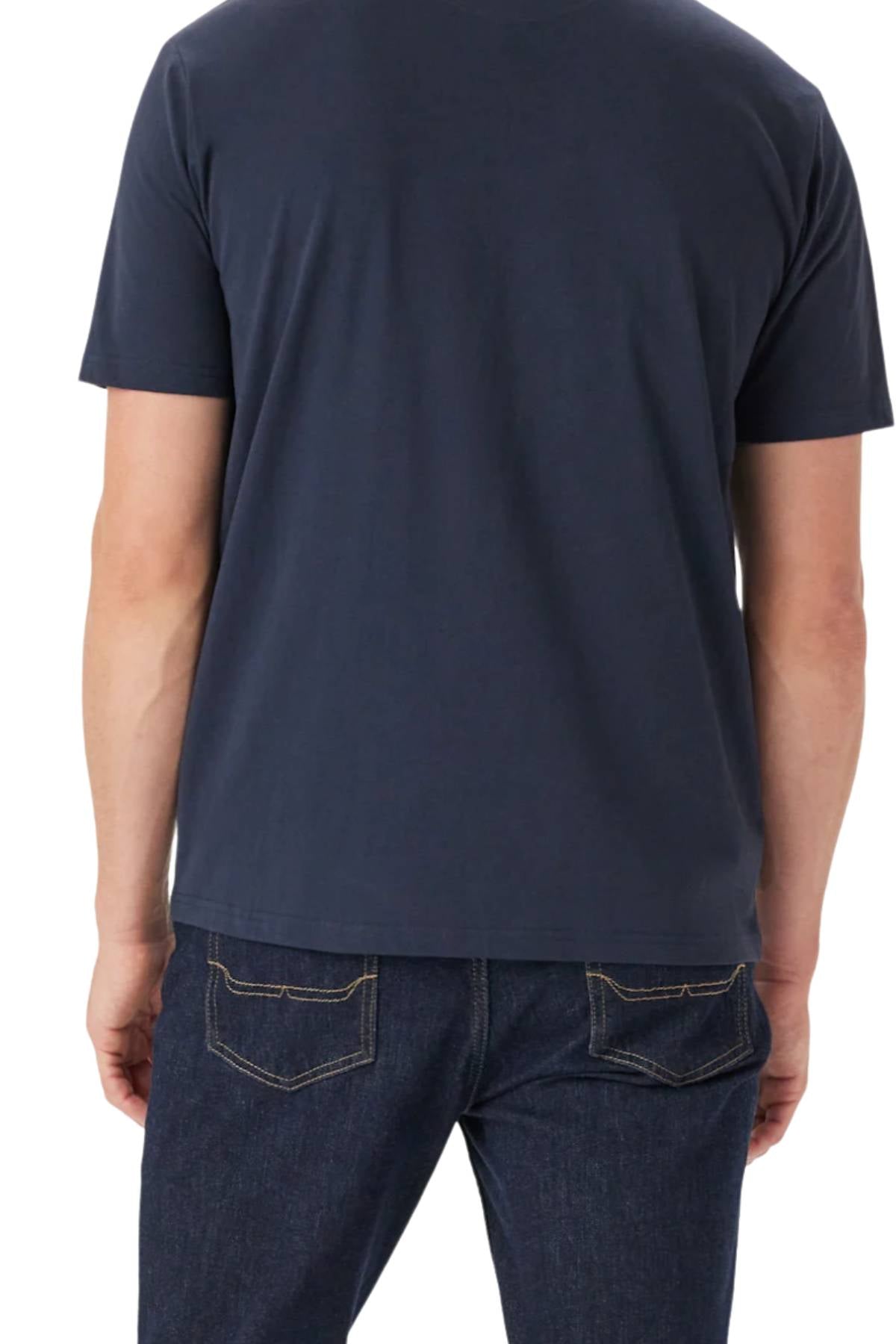 A person is standing with their back to the camera, wearing the RM Williams Bale T-Shirt in dark blue organic cotton and dark blue jeans with visible back pockets.