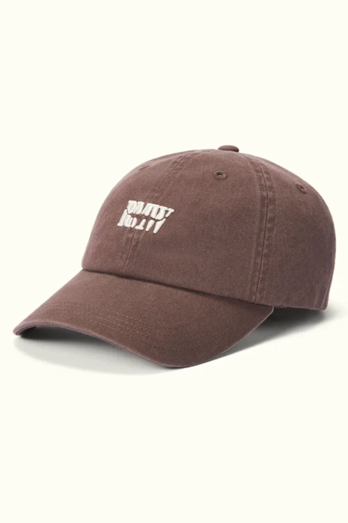 The RM Williams Branded Twill Cap is brown, made from organic cotton, and features a curved brim with white "DON'T TRIP." embroidery on the front and an adjustable strap. It is shown against a light background.