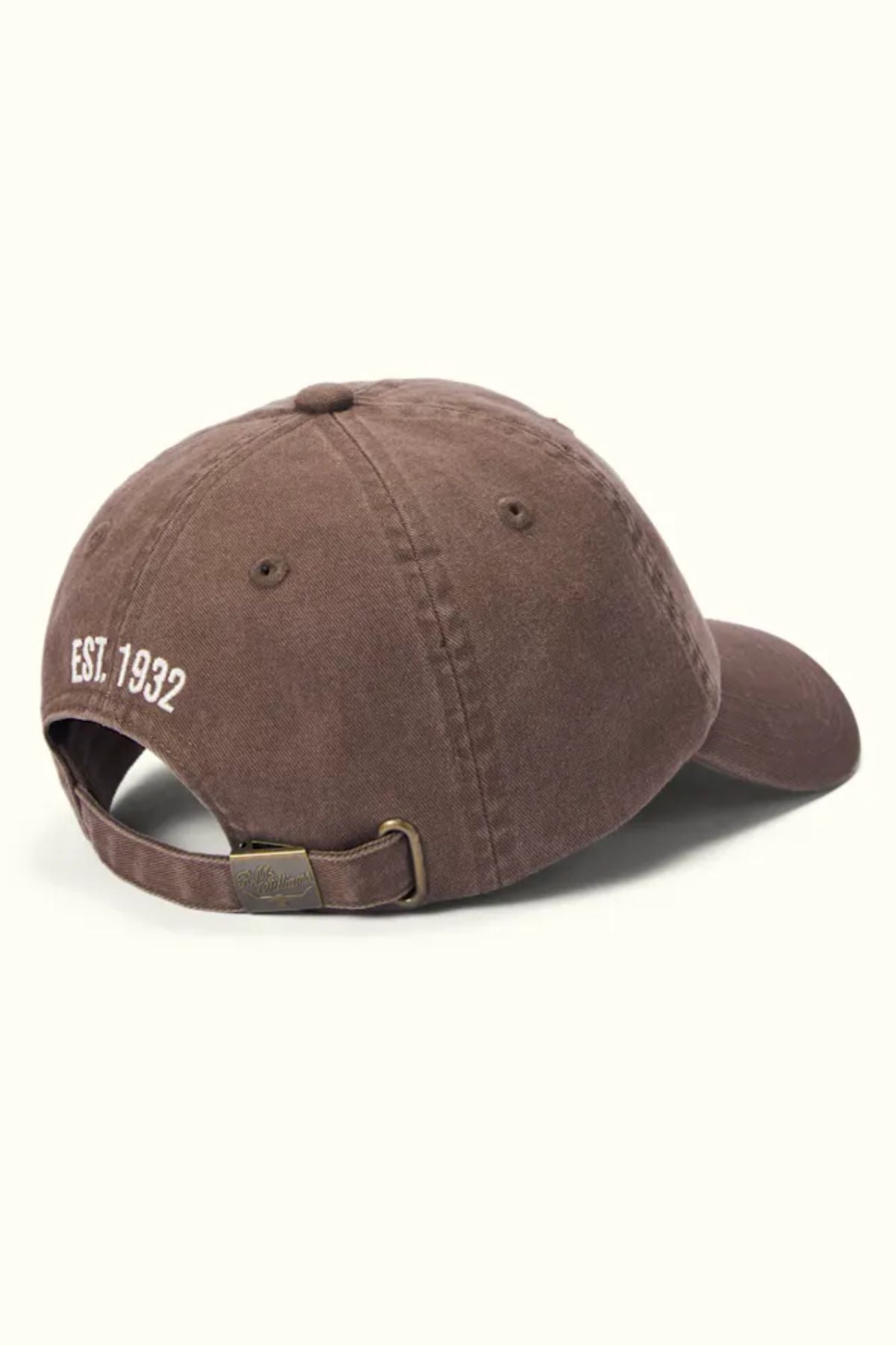 The RM Williams Branded Twill Cap is a brown organic cotton cap with visible stitching, an adjustable strap with a brass buckle, and "EST. 1932" embroidered in white on the back. Displayed against a plain light background.