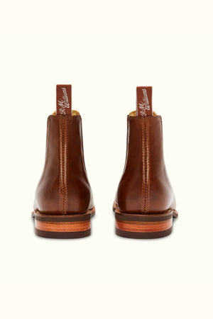 The RM Williams Comfort Craftsman Boot in brown pull-up leather, shown from the back with signature pull tabs featuring white script and contrasting rubber soles, is set against a plain light background.