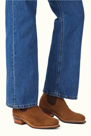 Person wearing blue denim jeans and RM Williams Comfort Suede Lady Yearling Rubber Sole Boots, standing on a light background.