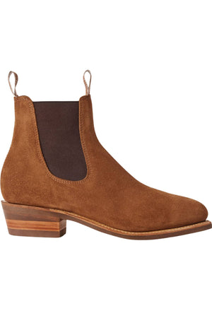 The RM Williams Comfort Suede Lady Yearling Rubber Sole Boot is a brown Italian suede Chelsea boot featuring a low wooden heel, elastic side panel, and front and back pull tabs inspired by classic RM Williams Boots.