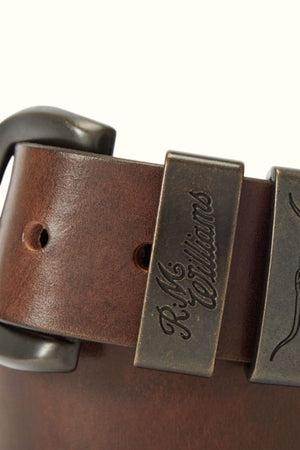 Close-up of the RM Williams Drover Belt in brown leather, featuring a metal buckle, double keepers, and a metal loop engraved with "R.M. Williams.