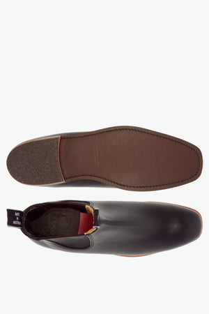 Top and bottom view of the RM Williams Erica Boot in black full-grain leather with a brown sole, elastic side panel, and heel pull tab on a plain white background.