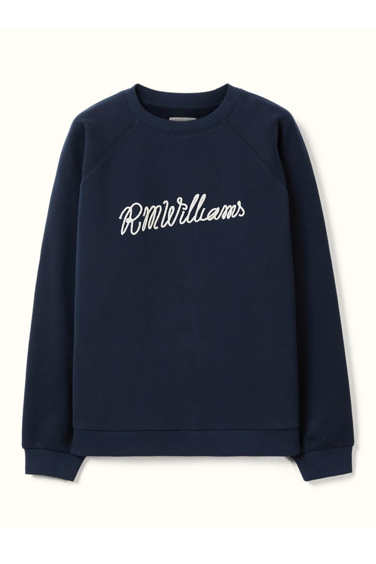 The RM Williams Lasso Brushed Sweatshirt is a navy crewneck with "R.M. Williams" embroidered in white cursive on the chest, crafted from Australian Good Earth Cotton and finished with ribbed cuffs and hem for a classic look.