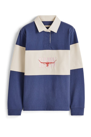 The RM Williams Narran Heritage 3 Panel Rugby is a heavyweight jersey shirt with wide navy blue and cream stripes, a cream collar, and an embroidered pink Heritage logo and "PAAW" text on the chest.