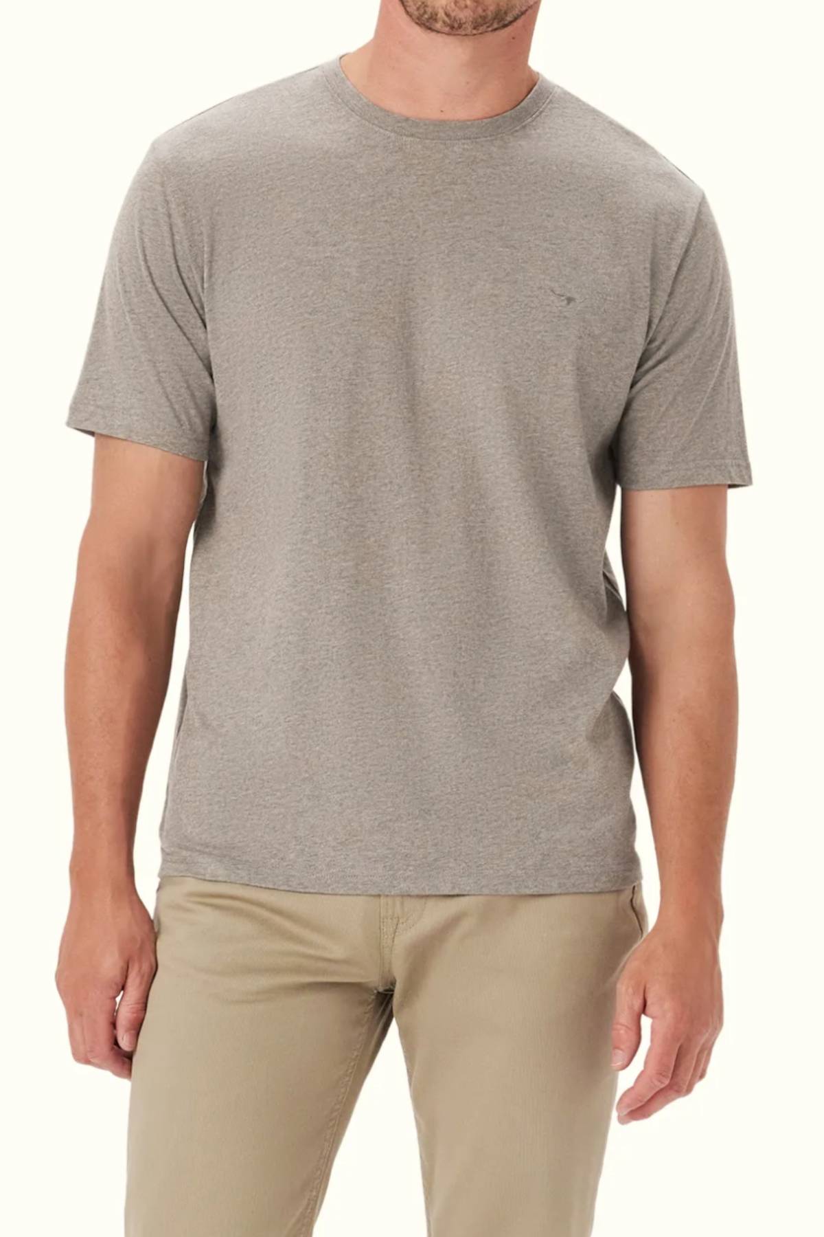 A man stands against a light background, wearing the RM Williams Parson T-Shirt in light gray with beige pants. His arms rest at his sides and his face is partially out of frame.