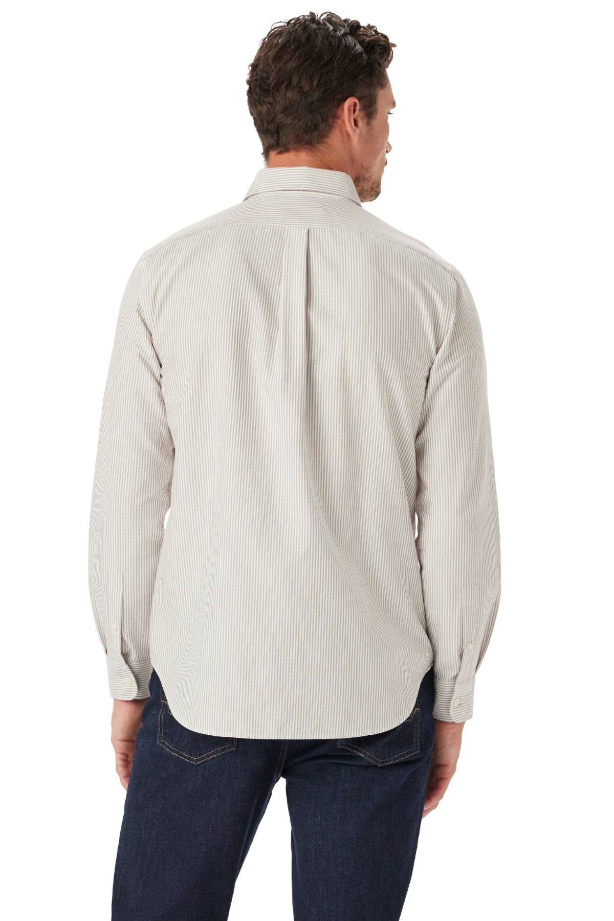 A man with short, wavy brown hair is seen from behind wearing the RM Williams Regular Oxford Stripe Shirt, a long-sleeve, light-colored striped oxford cotton shirt paired with dark blue jeans, standing against a white background.