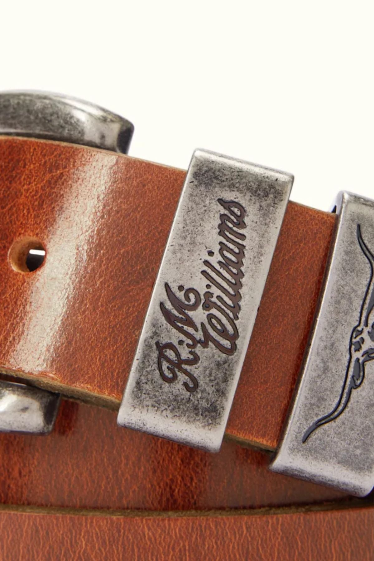 A close-up of the RM Williams Drover Belt, made in Australia from pull-up leather, with metal accents and an engraved "R.M. Williams" and longhorn symbol on the buckle, showcasing premium craftsmanship.