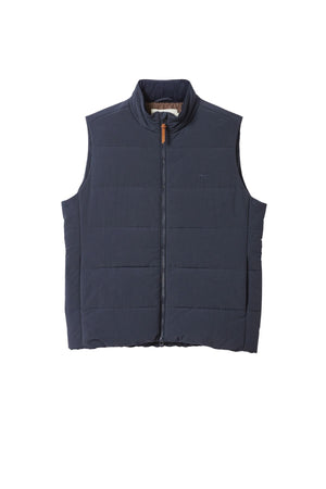 The RM Williams Padstow Vest is a navy blue, sleeveless puffer vest made from recycled nylon and PrimaLoft filling, with a front zipper, standing collar, and minimal detailing, shown on a white background.