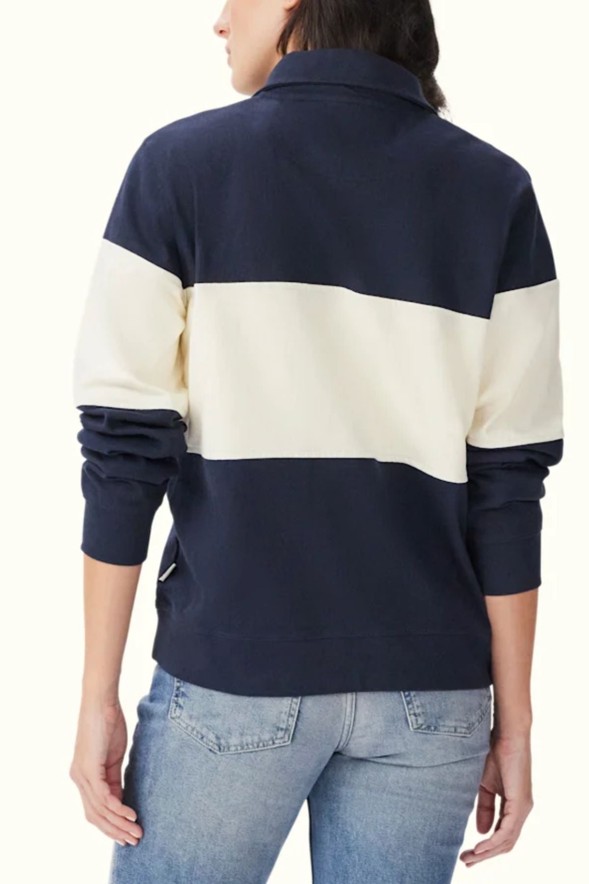 A person shown from the back wearing the RM Williams Trickett Panel Sweatshirt in navy and white stripes, paired with light blue jeans. The sweatshirt features a bold horizontal white panel across the middle.