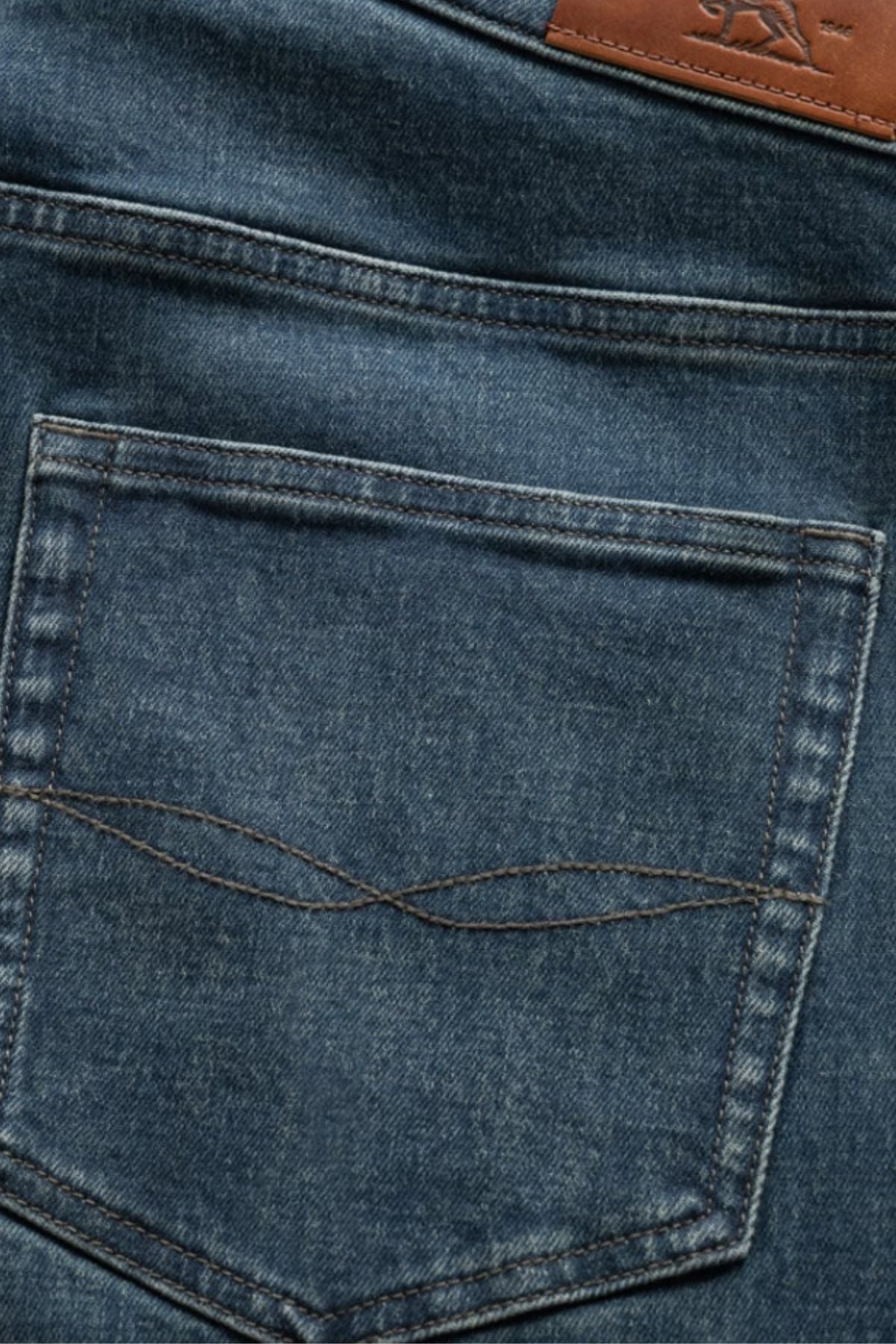 Close-up of the back pocket on Rodd & Gunn Kurow Relaxed Fit Italian Denim Jeans, featuring blue Italian denim, visible stitching, and a brown leather patch on the waistband.