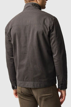 A man is seen from behind wearing a dark gray Rodd & Gunn Armitage Jacket with YKK zips and brown pants, set against a plain, light background that highlights the clothing.