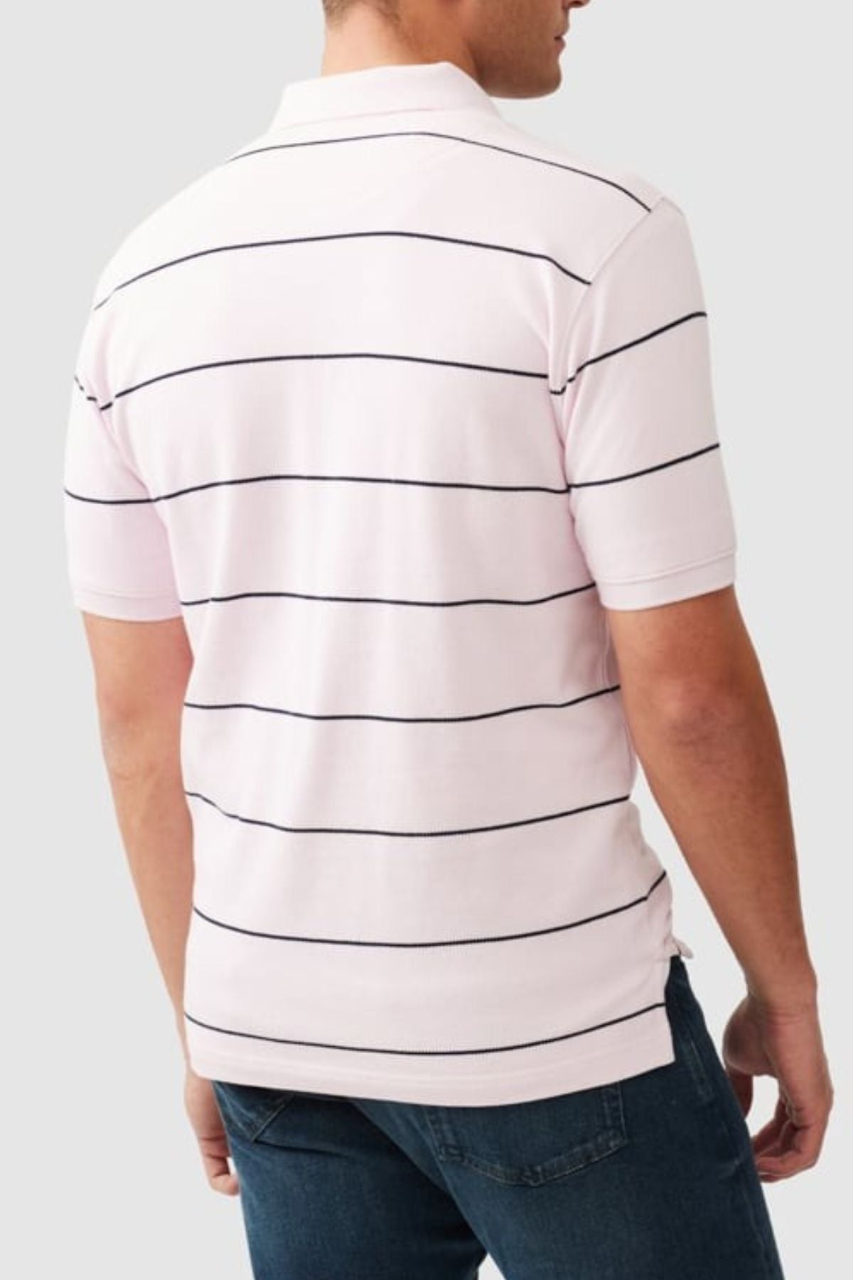 A man, seen from the back against a plain light gray background, wears a light pink Rodd & Gunn Glen Eden Polo with blue jeans.