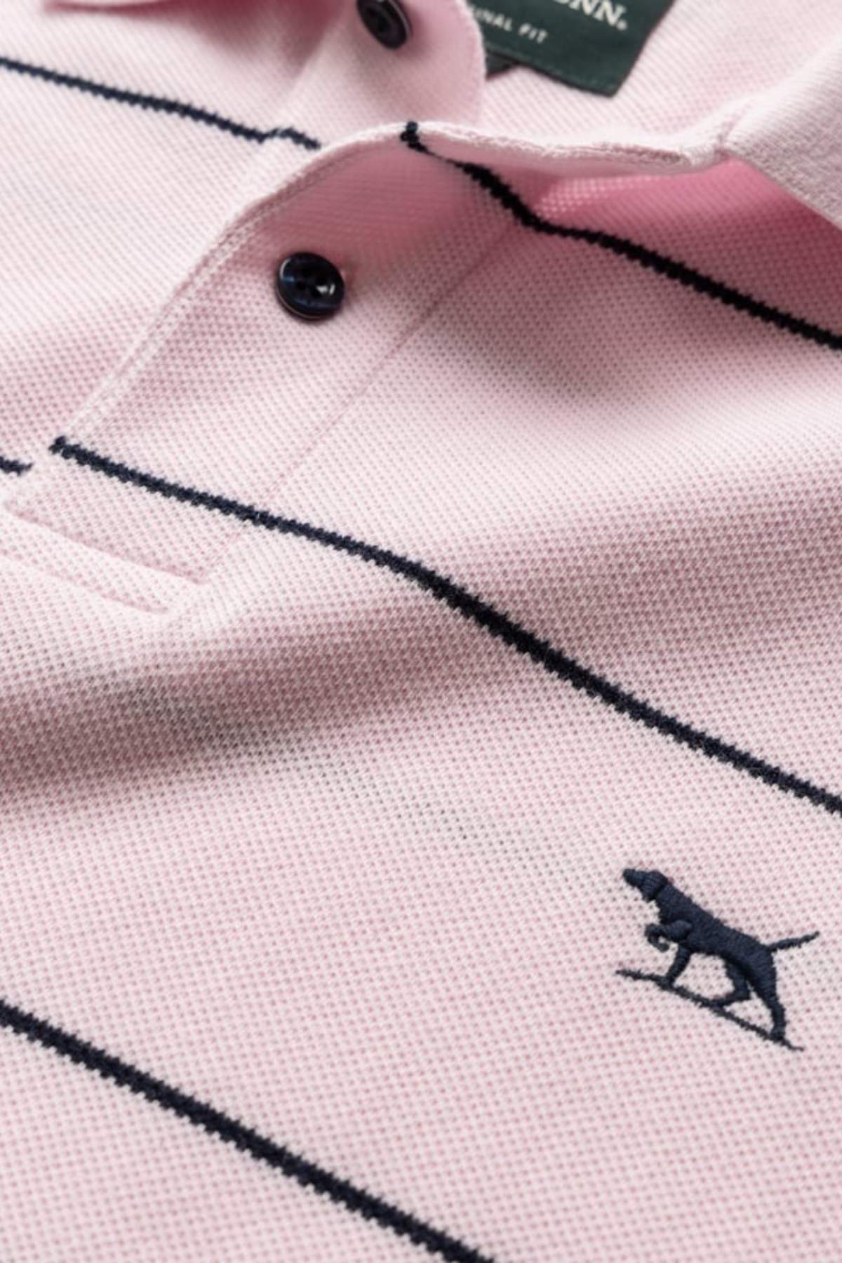 Close-up of the Rodd & Gunn Glen Eden Polo in light pink with thin black stripes, two black buttons, and a dark blue dog logo. Made from 100% cotton piqué for softness and breathable comfort.