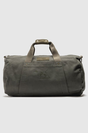 The Rodd & Gunn Ponsonby Road Duffle Bag is a dark green cotton canvas bag with short handles, a shoulder strap, and a subtle embroidered animal logo on the front against a plain light background.