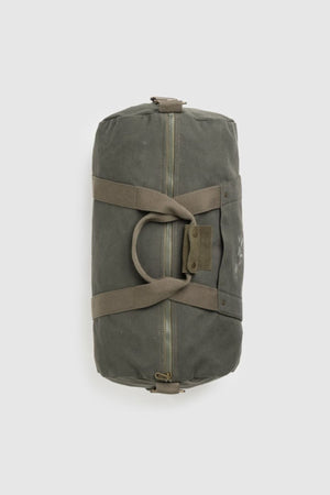 The Rodd & Gunn Ponsonby Road Duffle Bag, made from green cotton canvas with tan straps, a zipper closure, and buttoned handle strap, is shown lying flat on a plain light background.