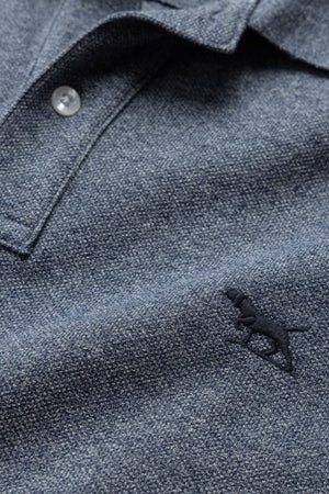 Close-up of a blue Rodd & Gunn The Gunn Polo, showcasing a textured finish, buttoned placket, and embroidered dog logo on the chest, made from premium Australian cotton for a modern fit.