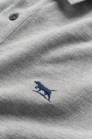 A close-up of the Rodd & Gunn The Gunn Polo in light gray, made from premium Australian cotton, with a dark blue stitched dog logo on the left chest and a collar button.
