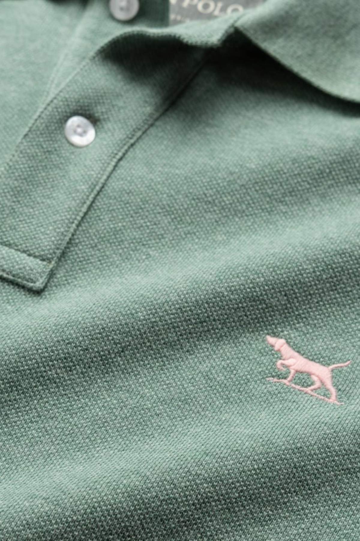 The Rodd & Gunn The Gunn Polo is a modern fit green shirt made from premium Australian cotton, featuring white buttons and a pink embroidered dog logo on the lower right side.