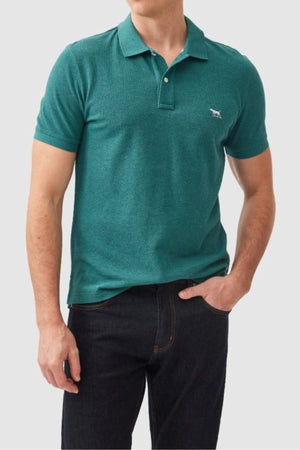 A man wears the Rodd & Gunn The Gunn Polo in teal, made from Australian cotton with a small embroidered animal logo, paired with dark jeans. He stands with one hand in his pocket against a light background. Modern fit offers a clean, classic look.