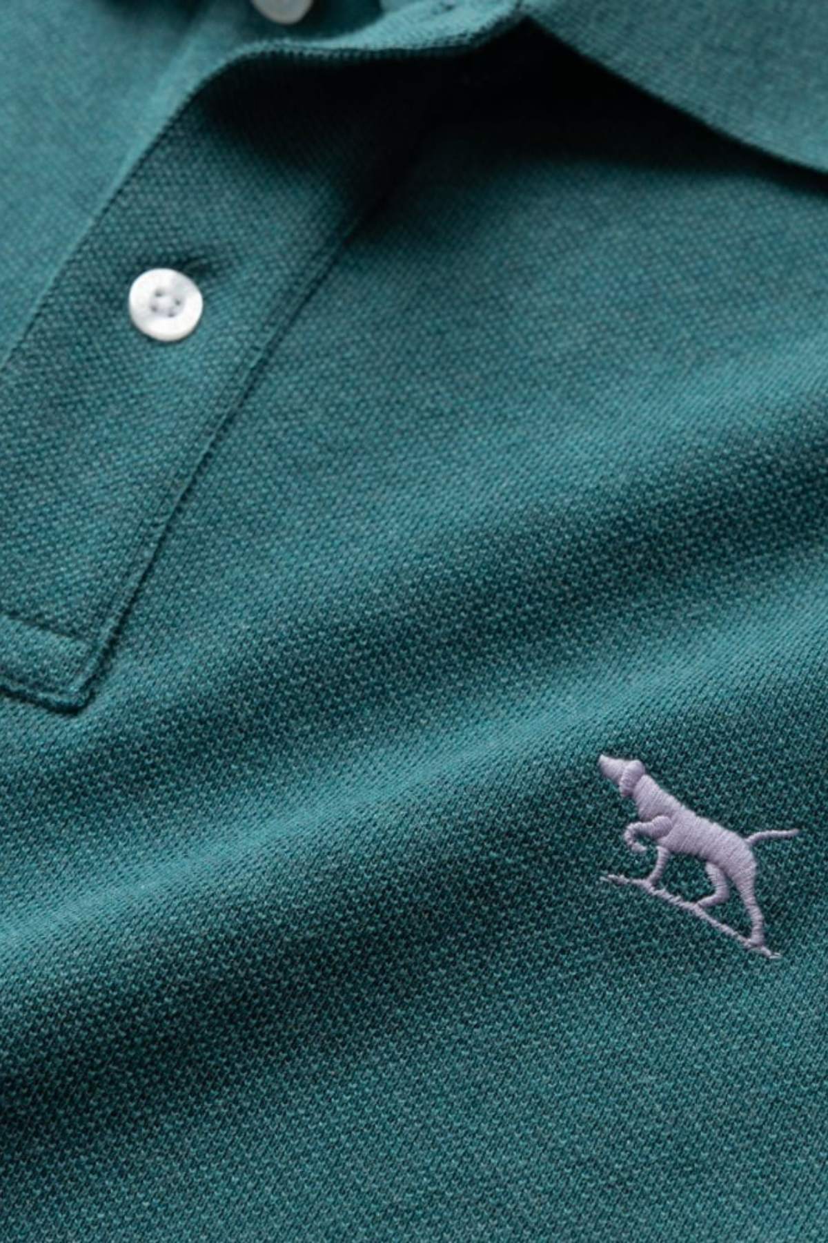 Close-up of the Rodd & Gunn The Gunn Polo in modern fit teal, made from premium Australian cotton with white buttons and a small light lavender embroidered dog logo on the chest.