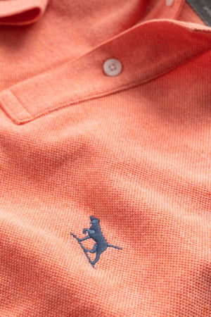 Close-up of a modern fit orange Rodd & Gunn The Gunn Polo, crafted from soft Australian cotton with white buttons and a navy embroidered dog logo on the chest.