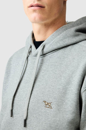 A person dressed in the Rodd & Gunn Otago Hoodie, featuring a light gray hue, drawstrings, and a subtle embroidered dog logo on the chest. Made from soft brushed back fleece, this Australian Cotton hoodie is depicted in a photo cropped to highlight only the lower face and upper body.