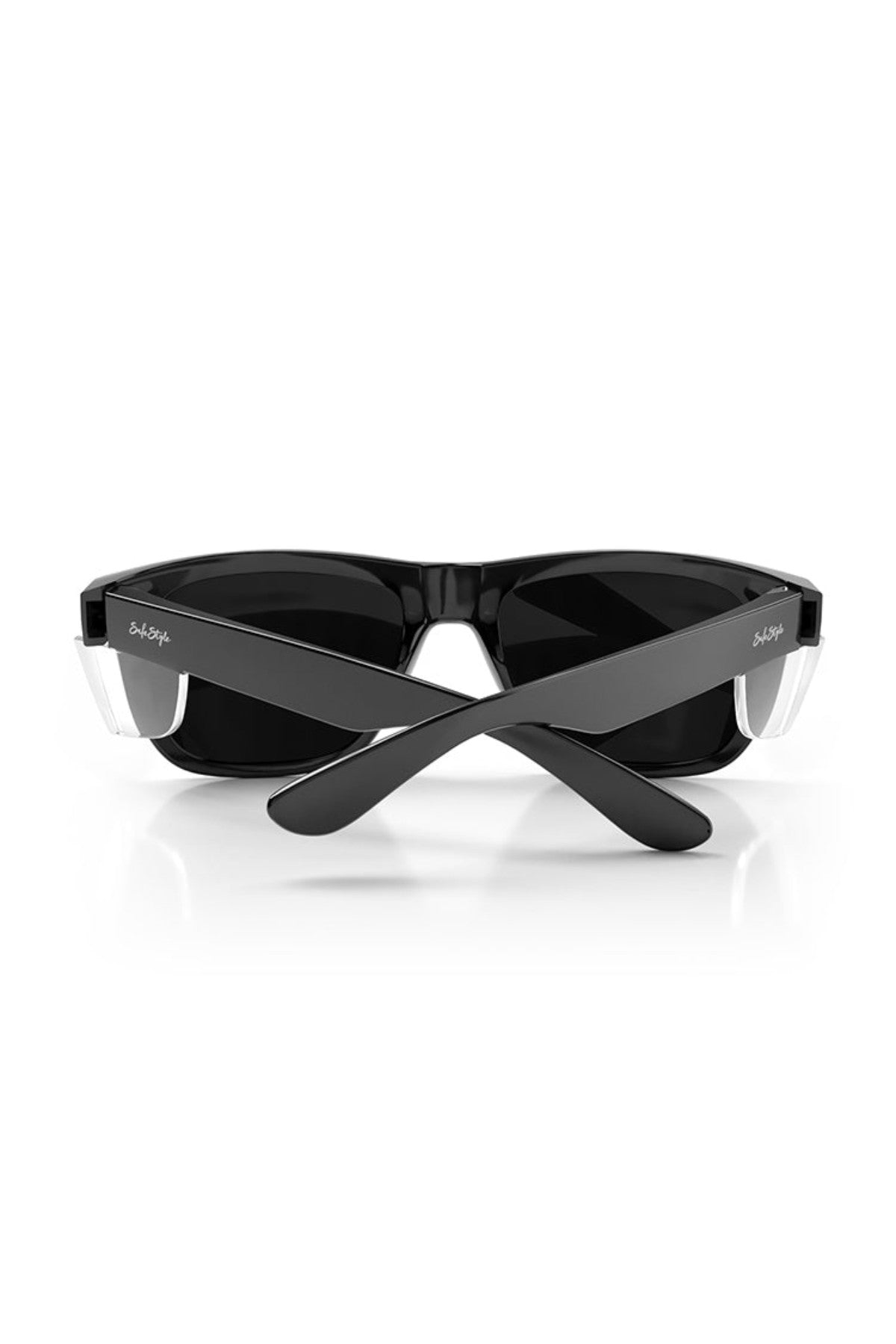 The SafeStyle Fusions XL sunglasses feature a sleek black frame with a glossy finish, polarised lenses for UV protection, and engraved brand name near the hinge. Their crossed arms are highlighted against a white background, showcasing these stylish shades.