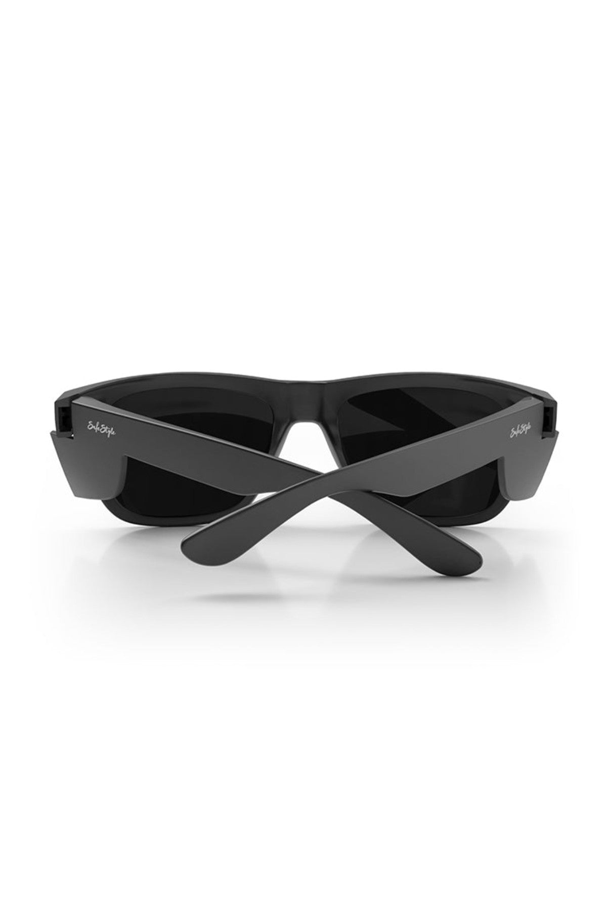 The SafeStyle Fusions XL Matte Black Frame Polarised Lens sunglasses are shown from the rear with their arms crossed over each other. The dark, polarized lenses are encased in a thick, durable frame. Both arms feature small white logos near the hinges, and the background is plain white.