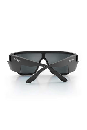 A pair of stylish black sunglasses with rectangular blue lenses, featuring wide arms and the brand name "SafeStyle" printed in white on the arms. Made from recyclable polycarbonate with matte black frames, these SafeStyle Primes Matte Black Frame Reflectors also offer UV protection. They are shown from the back, resting on a white surface.