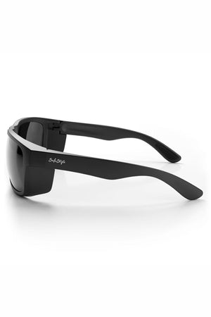The SafeStyle Rapids Matte Black Frame Tinted Lens sunglasses feature wraparound black frames with thick arms, UV protection, and shatterproof lenses. The "SafeStyle" brand name is displayed in white on the arm, shown side-on against a white background.