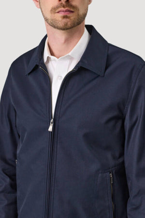 A man models the Savile Row James Zip Front Jacket in dark navy over a white collared shirt, shown from shoulders to waist against a plain light gray background.