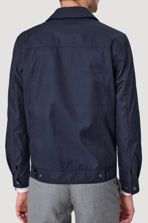 A man is shown from the back wearing a navy blue Savile Row James Zip Front Jacket with a classic collar, buttoned cuffs, and adjustable side tabs at the hem, paired with light gray pants.