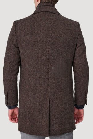 A person wearing a brown herringbone Savile Row Jared Removable Collar Coat with a tailored fit and back vent is seen from behind, the pure wool draping elegantly as their hands rest at their sides.