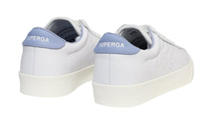 The Superga 2843 Club S Comfort Leather Sneakers feature white leather with light blue heel accents and the brand name in white text. A thick vulcanized gum sole ensures style and durability, captured beautifully from a rear three-quarter angle.