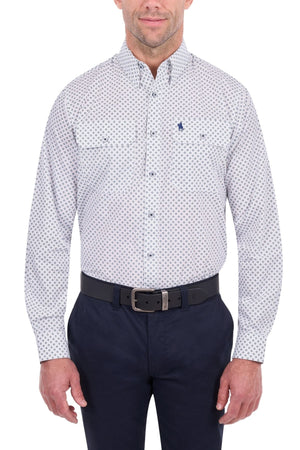 A man wearing the Thomas Cook Albie Shirt—a 100% cotton white button-up with a small blue pattern—paired with dark pants and a black belt, stands against a white background.