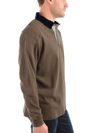 A man stands in profile against a white background, wearing the Thomas Cook Bill Rugby—a brown cotton jersey knit long-sleeve shirt with a black collar and padded shoulder detailing.