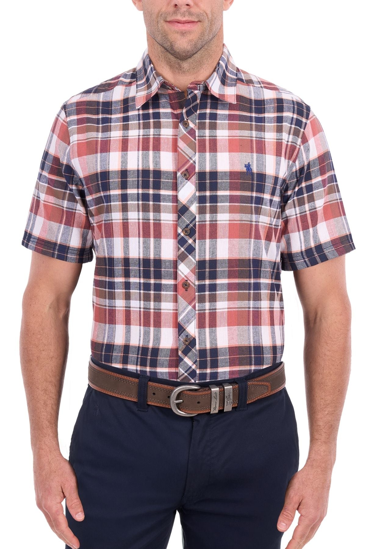 A man wearing the Thomas Cook Ethan Short Sleeve Shirt, featuring a red, white, and navy plaid pattern, paired with navy pants and a brown belt, stands against a white background.